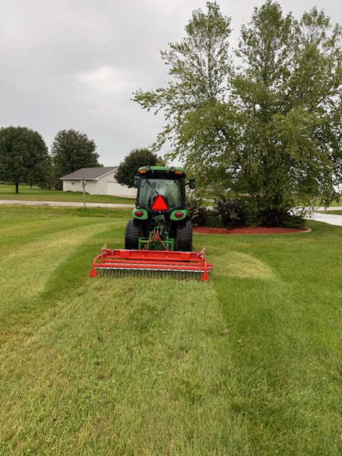 Crappy Lawn Care tractor and dethatching equipment on a residential lawn
