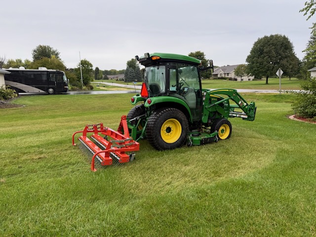Crappy Lawn Care tractor and dethatching equipment on a residential lawn